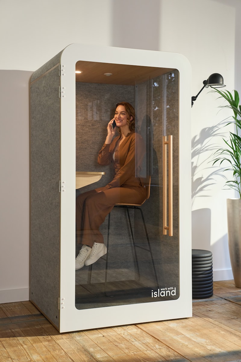 Woman taking a private phone call inside a single-person acoustic phone booth